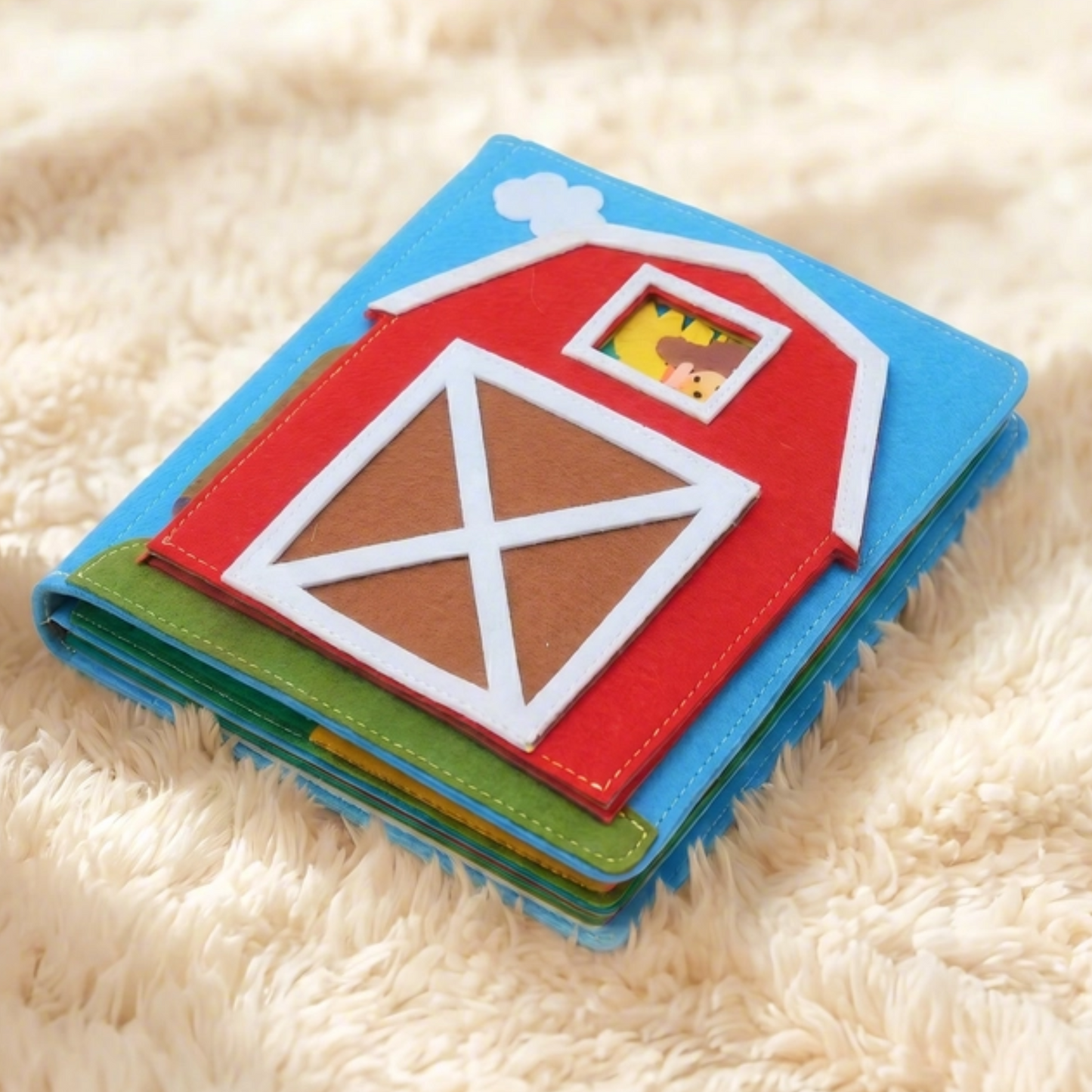 Children's soft early learning book with a barn and farm theme design on a fluffy white surface