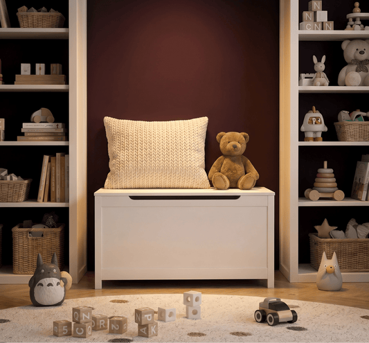 White storage toys bench with a pillow and teddy bear in a room with shelves and toys.