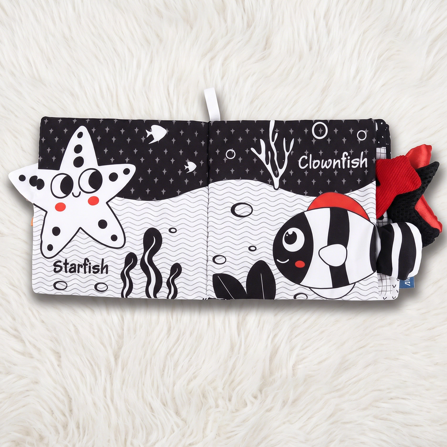 Children's soft book with starfish and clownfish illustrations on a white background