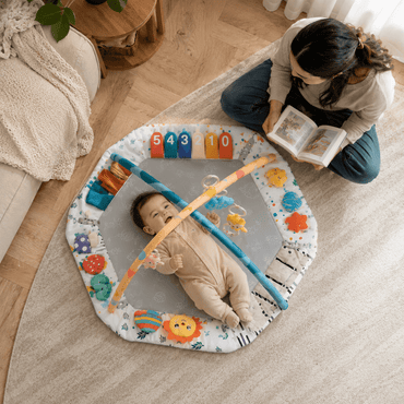 Overhead view of a mom sitting beside her baby on the hexagonal play gym mat