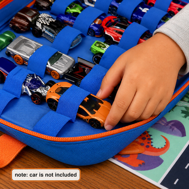 A close-up of a blue fabric toy car organizer with elastic loops holding multiple toy cars. A child's hand is placing an orange toy car into one of the loops.