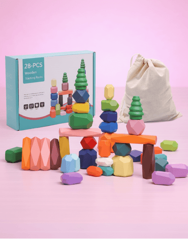 Wooden stacking rocks balancing toy set on a pink background.