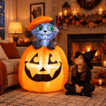 5 ft kitty cat pumpkin Halloween inflatable in a cozy living room beside a sofa and fireplace with a girl in a witch hat