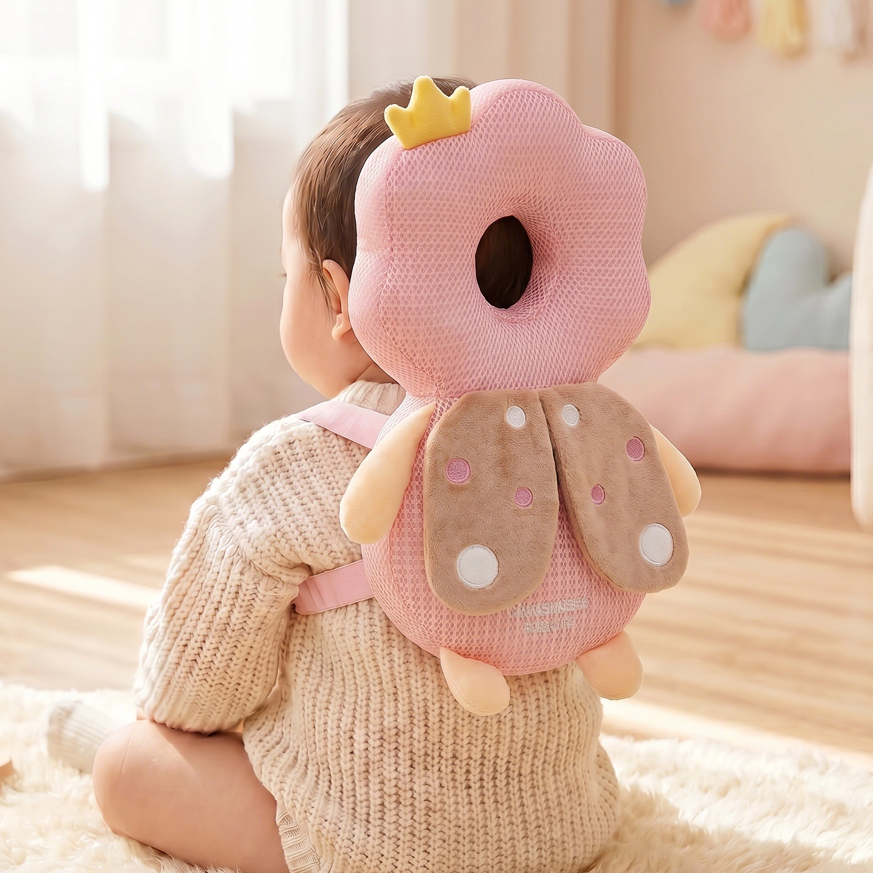 Baby wearing a pink donut-shaped head support pillow in a cozy room.