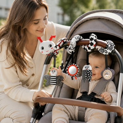 Woman sitting next to a baby in a stroller with various baby toys attached.