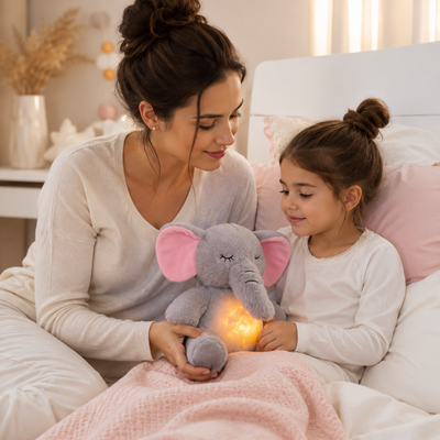 Woman and child sitting on a bed holding a glowing elephant plush toy.