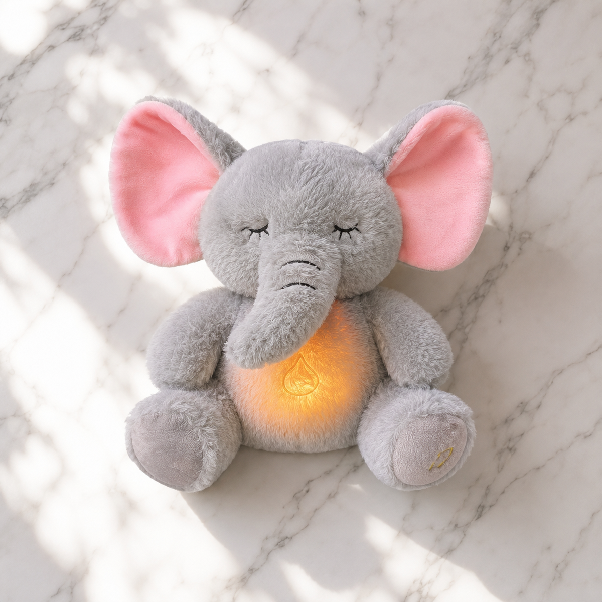 Plush elephant toy with a warm light on a marble surface