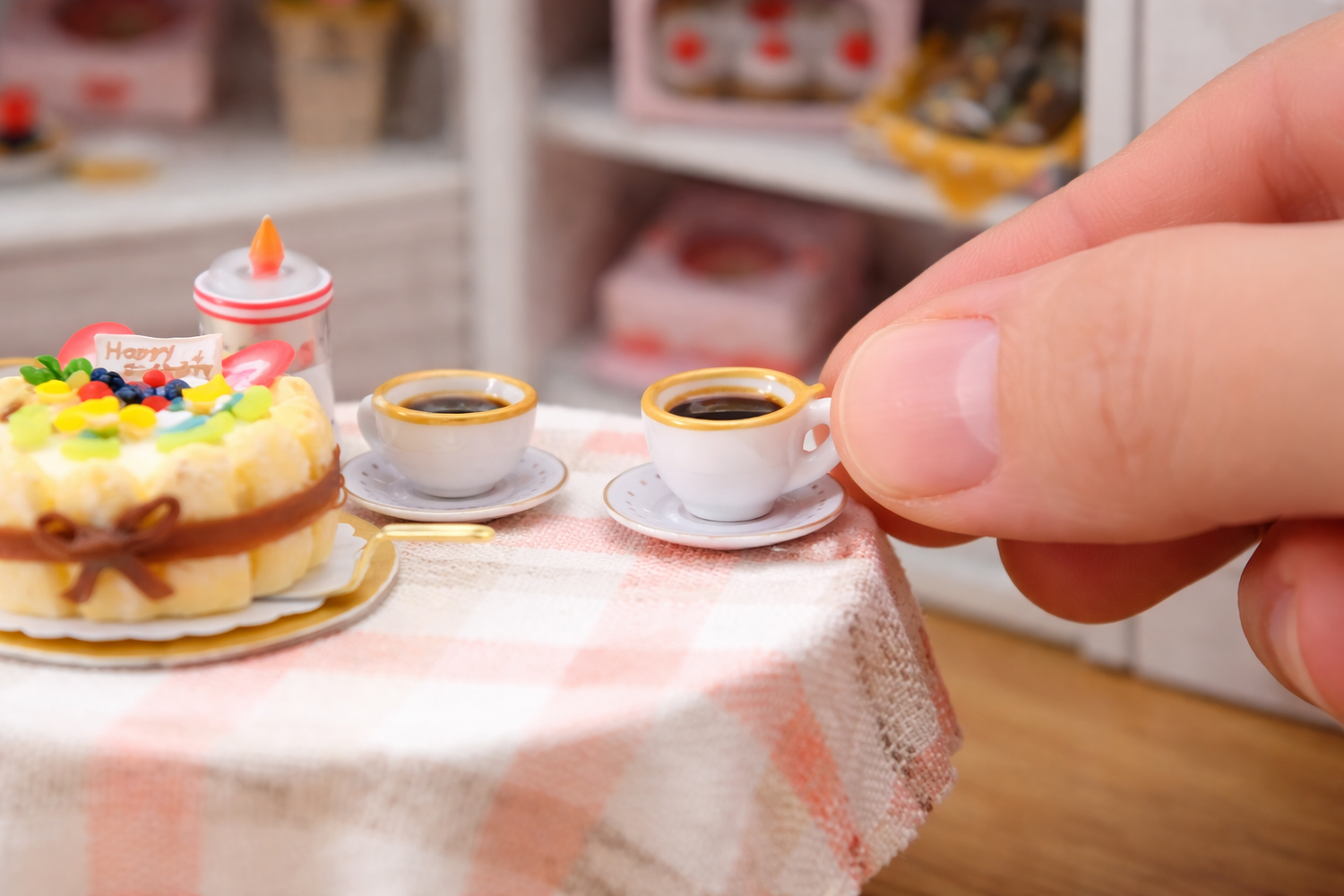 Miniature table setting with a cake and coffee cups, held by a hand - crafting mini dollhouse birthday gift