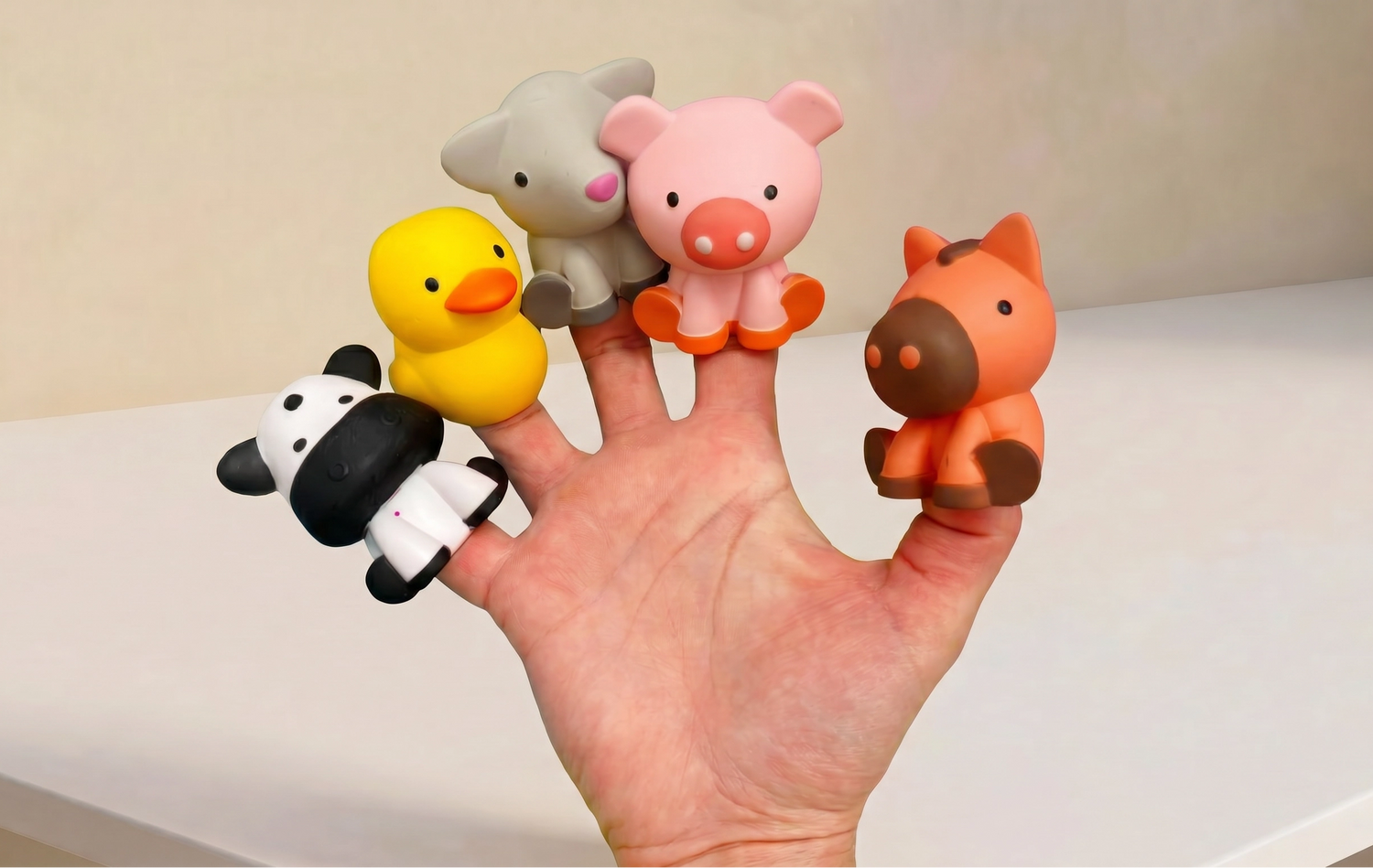 Hand with finger puppets shaped like animals on a plain background