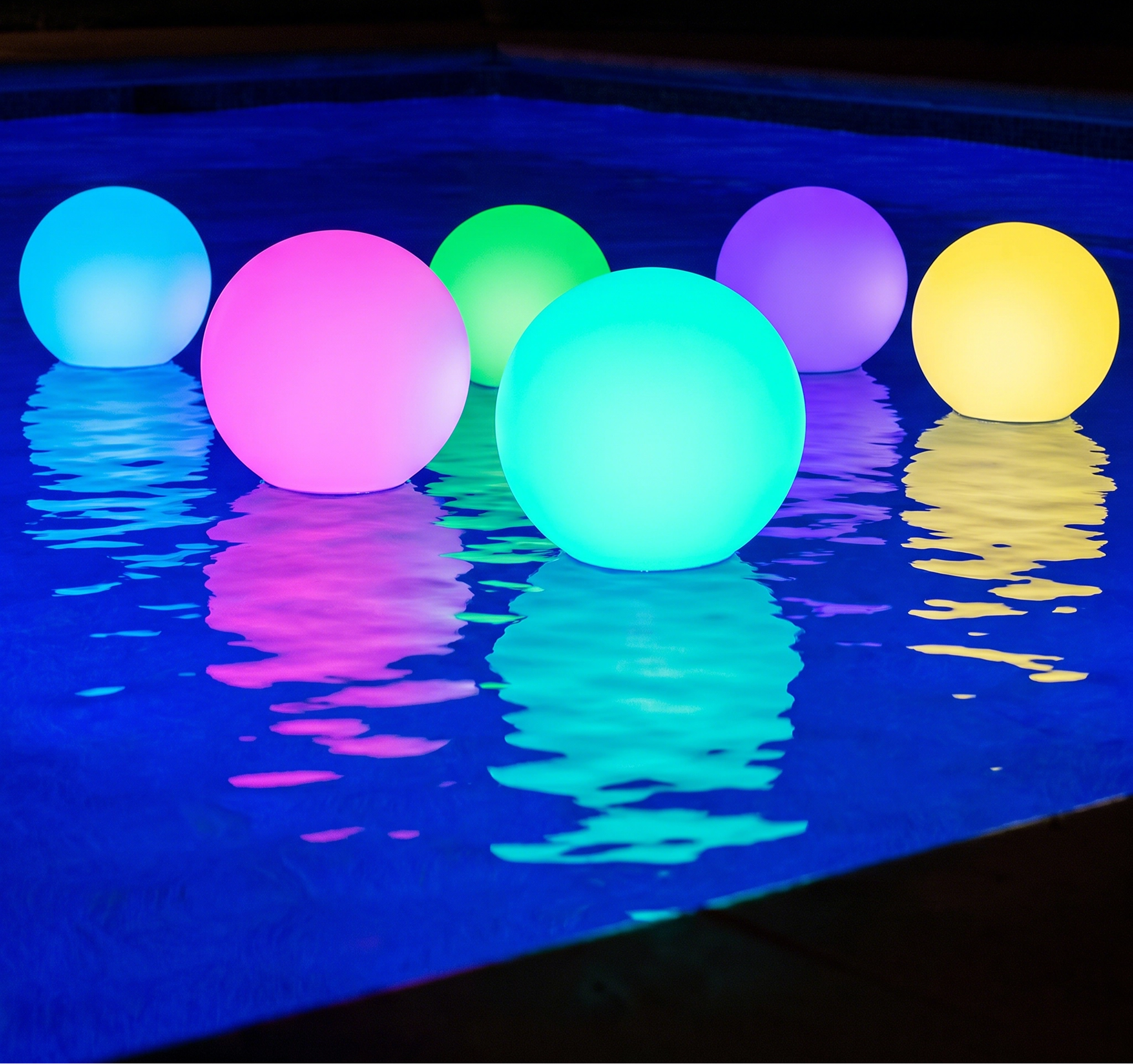 Colorful glowing balloons floating on water at night