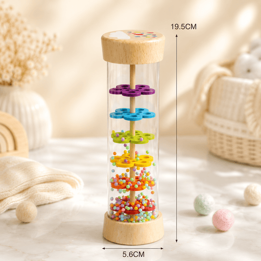 A wooden and clear plastic bead toy tower shown on a soft cream tabletop with decorative props in the background.