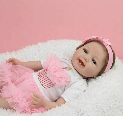 Baby doll in a pink outfit with a bow on a white surface against a pink background