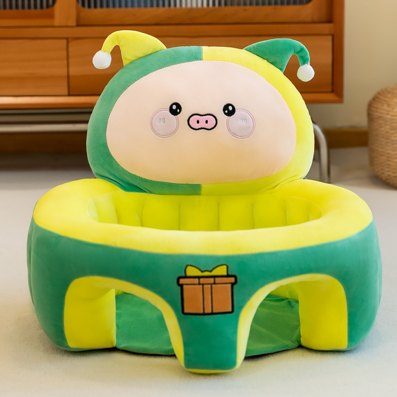 Green and yellow plush toy with cartoon face on a wooden floor