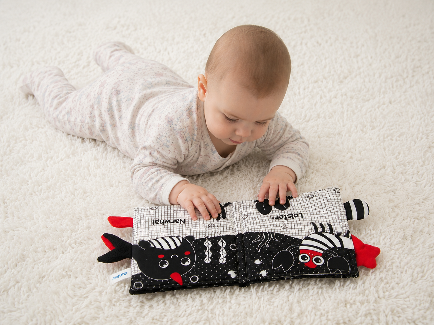 Baby playing with a soft toy on a white carpet