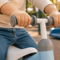 Toddler hands gripping anti-slip handlebar on blue baby balance bike