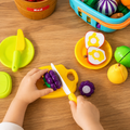 Child using a play knife to cut pretend food, building fine motor skills, a birthday gift for a 2 year old girl
