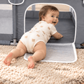 Baby crawling through the fold-down door panel of the mesh playpen